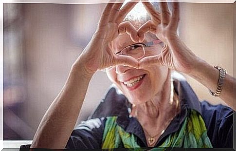 Happy elderly woman making heart with hands to age healthily