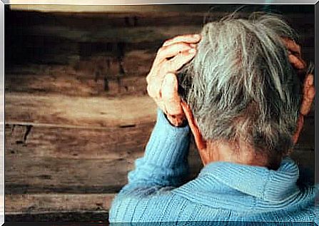 Elderly person with hands on temples.