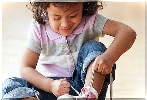 Little girl is tying her shoes