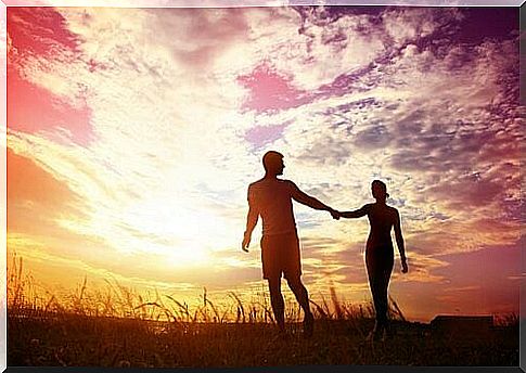 Couple-walking-by-the-hand-at-sunset